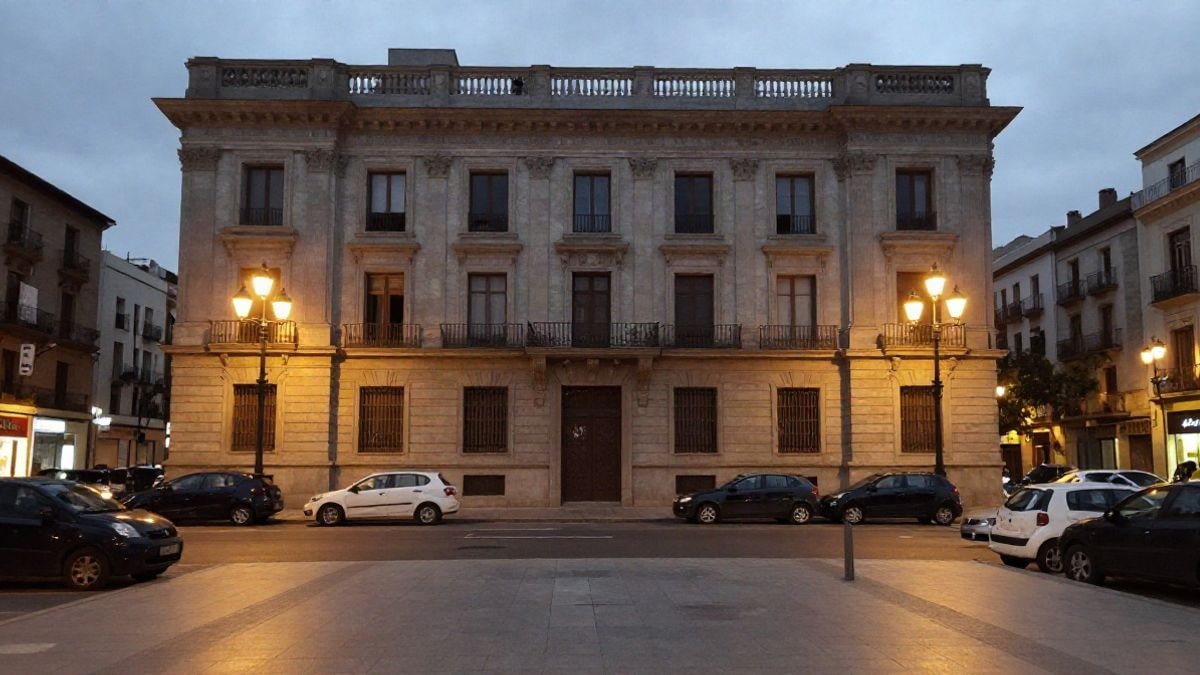 Imagen ilustrativa: fachada de un edificio institucional iluminada por farolas en una calle urbana nocturna