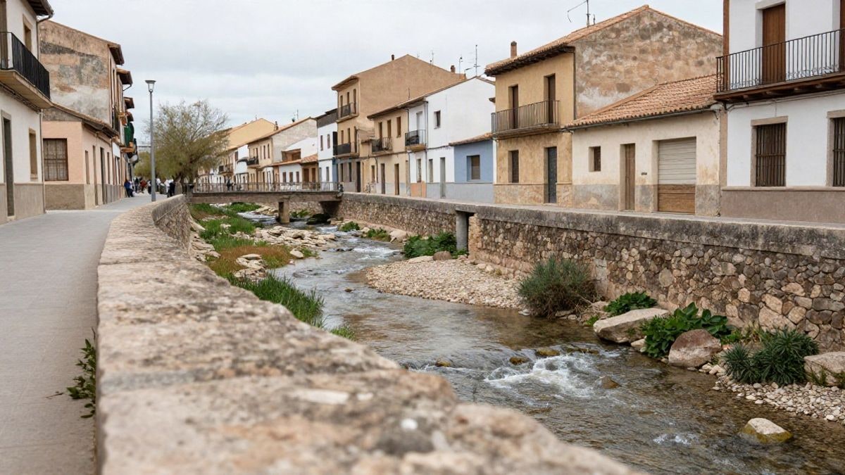 Imagen ilustrativa: cauce de un río urbano con muros de piedra y edificios modestos al fondo