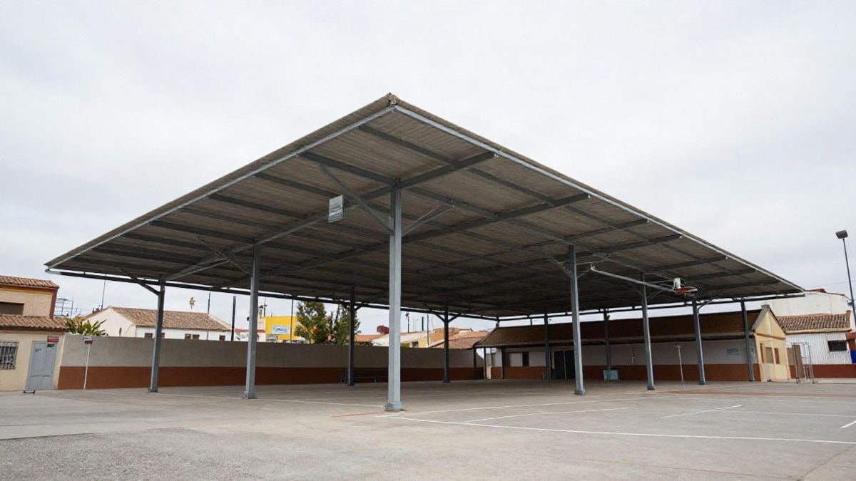 Imagen ilustrativa: cancha de baloncesto escolar con estructura de cubierta metálica en construcción