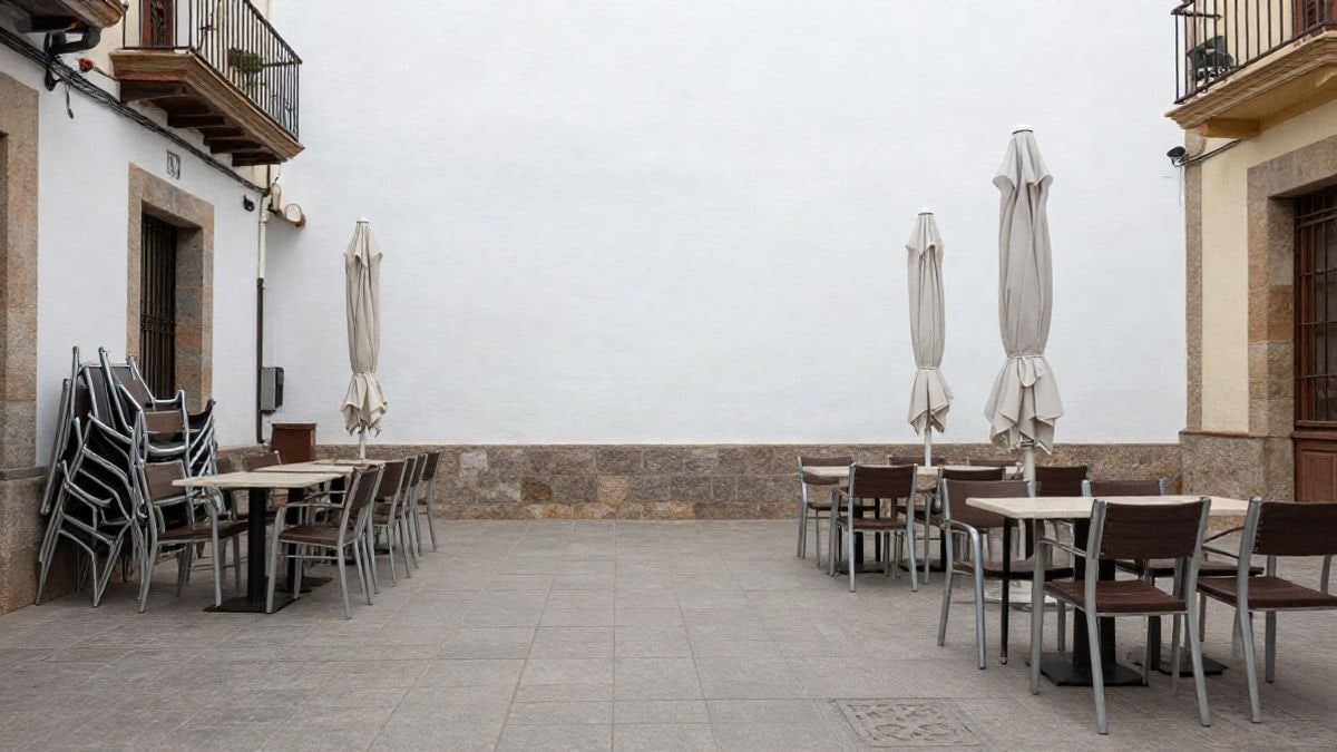 Imagen ilustrativa: terraza de bar vacía con mesas y sillas apiladas en una calle corriente