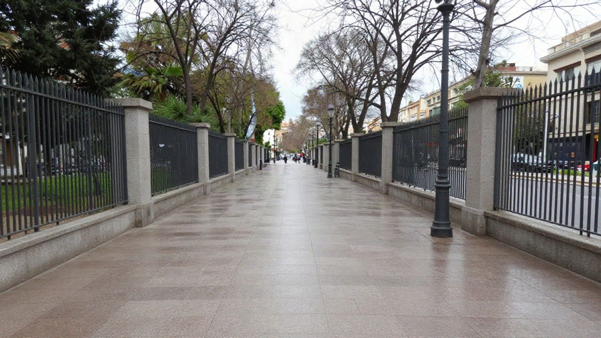 Imagen ilustrativa: camino de parque urbano mojado con vallas de cierre bajo cielo nublado