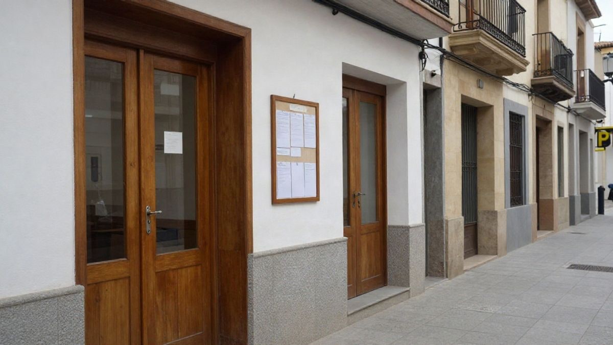 Imagen ilustrativa: pasillo de oficina municipal con puertas de madera y tablón de anuncios vacío