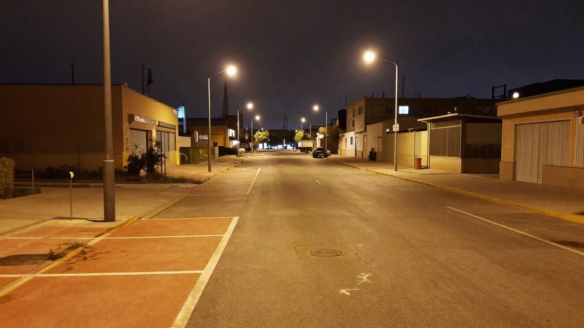 Imagen ilustrativa: calle de polígono industrial de noche con plazas de aparcamiento pintadas de naranja bajo farolas