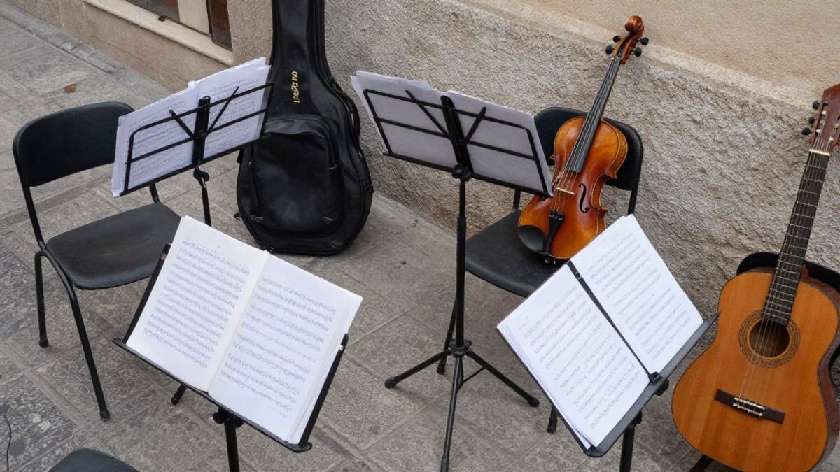 Imagen ilustrativa: vista cenital de un aula de música con atriles, partituras e instrumentos sobre sillas
