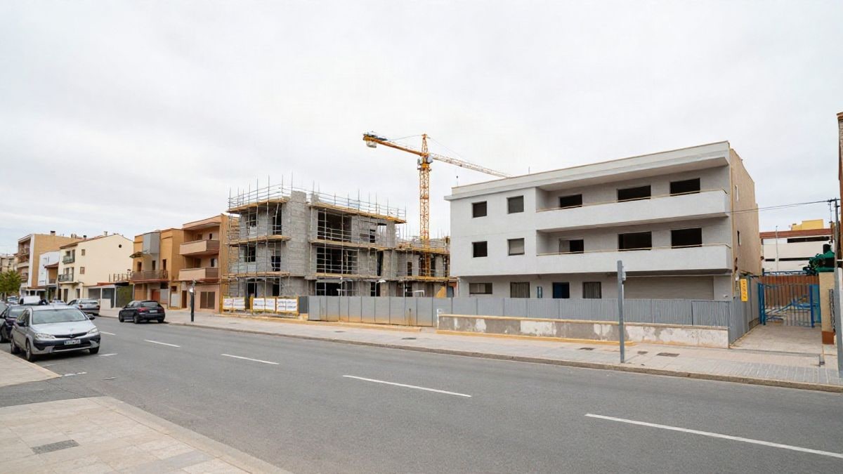 Imagen ilustrativa: edificios de viviendas en construcción en una calle urbana con andamios y una grúa