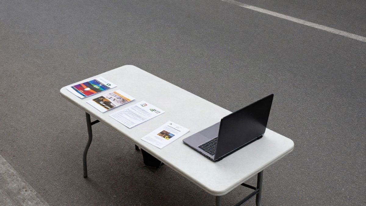 Imagen ilustrativa: vista cenital de un puesto vacío en una feria de empleo con folletos y un portátil