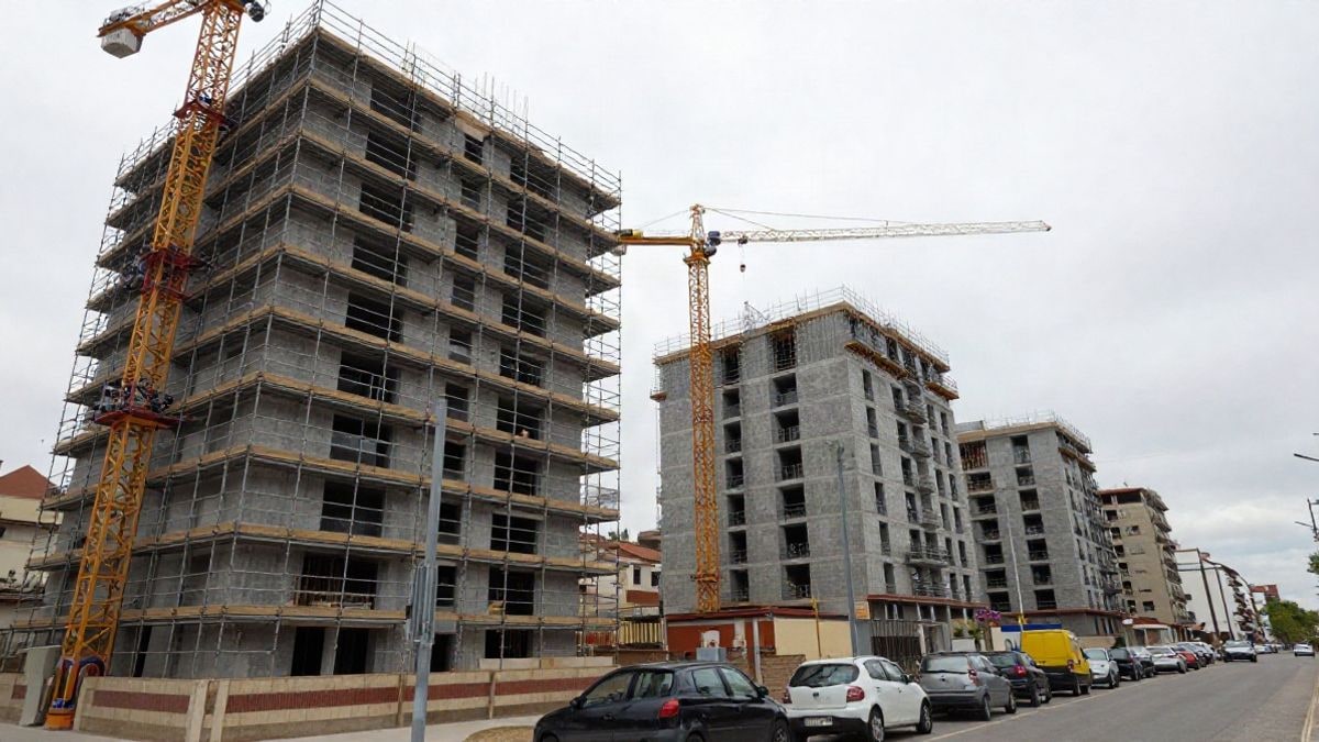 Imagen ilustrativa: bloques de viviendas en construcción vistos desde la calle con grúas y andamios